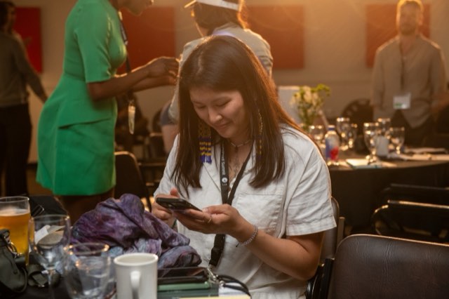 An attendee smiling at her phone during a golden hour dinner at the Future Proof Creator Summit 2026